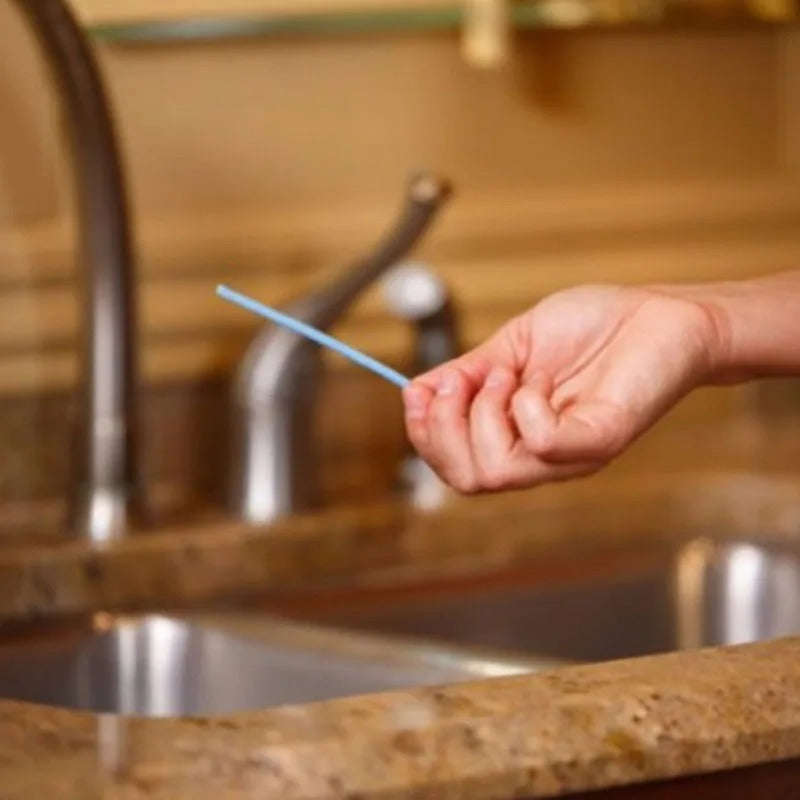 DrainCleaner Reinigungsstäbchen wird nahe einem Wasserhahn in der Küche gehalten