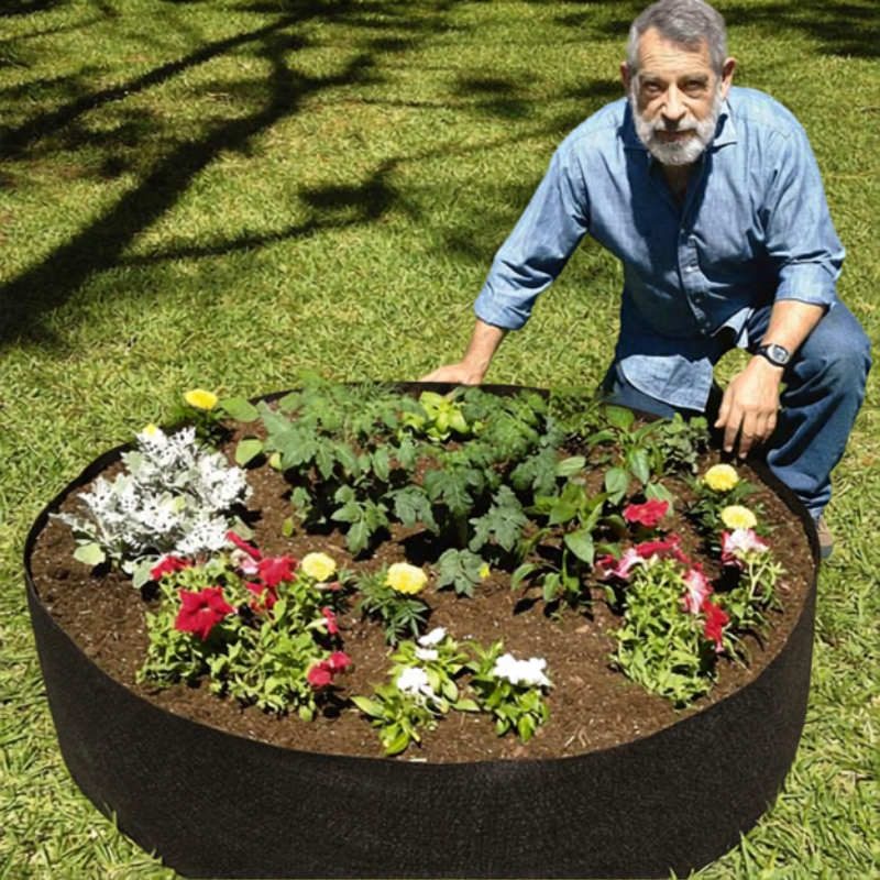 Gärtner kniet bequem am erhöhten GardenBed Hochbeet mit Blumen