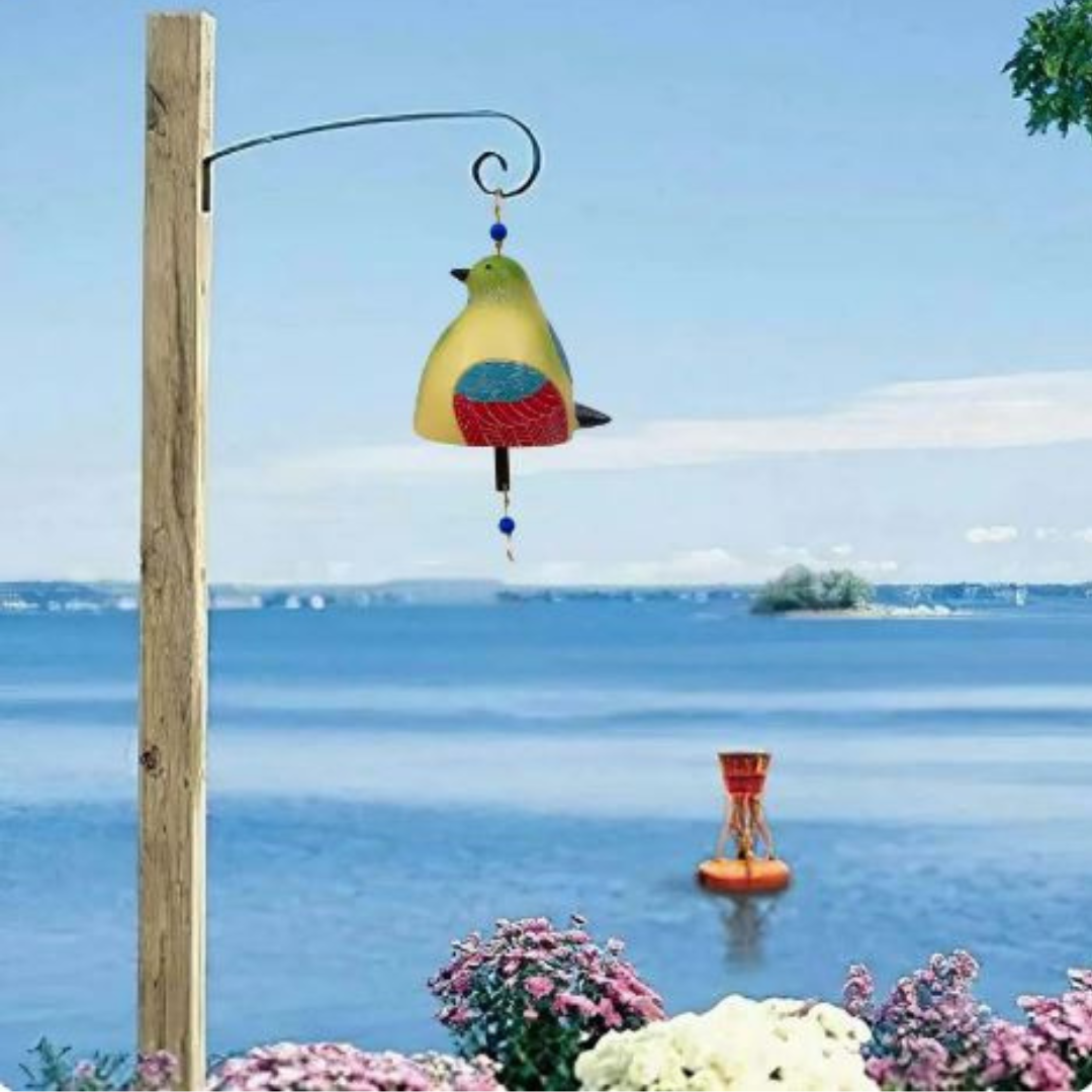 BirdChime Windspiel an einem Gartenhaken über einer Blumenwiese am Wasser